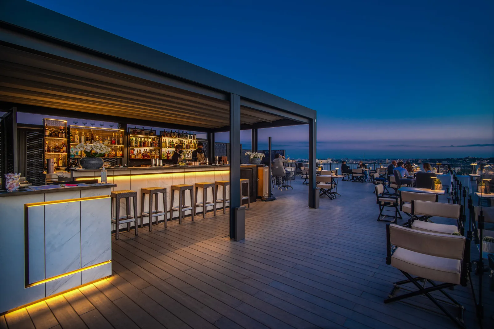 Beleuchteter Bartresen der Dachterrasse in der blauen Stunde
