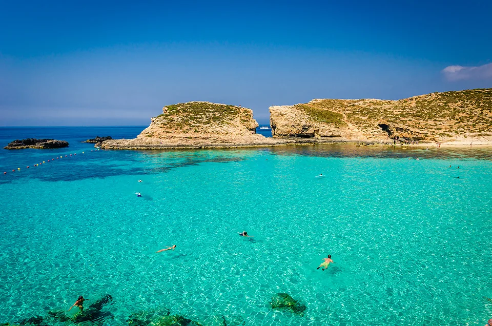 Türkisfarbenes flaches Wasser der Blauen Lagune mit Schwimmern vor Felsklippen