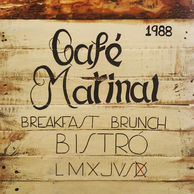 Handgemaltes Holzschild des Cafés mit Schriftzug, Jahreszahl 1988 und Öffnungstagen