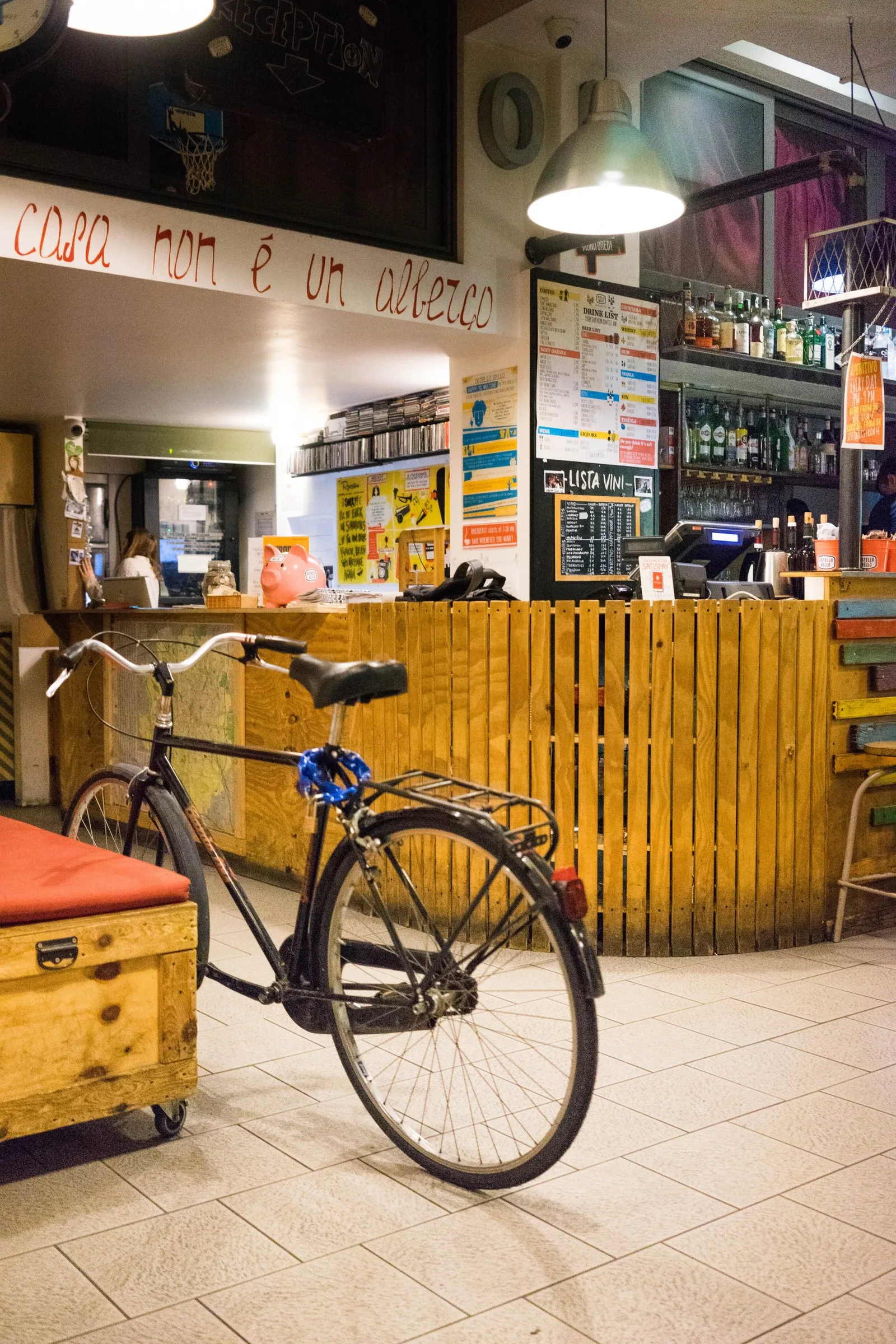 Fahrrad vor der Rezeption mit Holztresen, Getränkekarte und Wandaufschrift