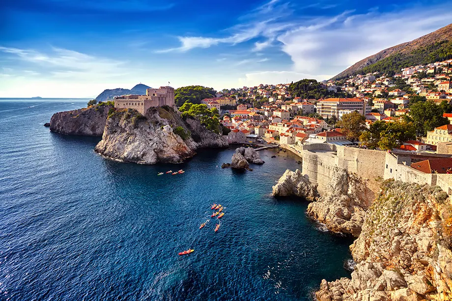 Dubrovniks Stadtmauer und Altstadtdächer über der Küste, Kajaks auf dem blauen Meer
