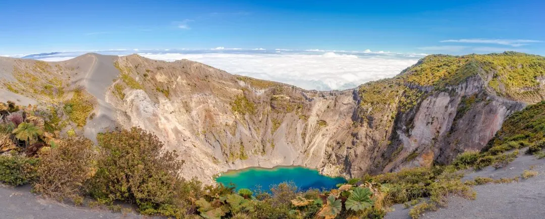 Panorama des Kraters mit türkisgrünem See am Vulkan Irazú über dem Wolkenmeer