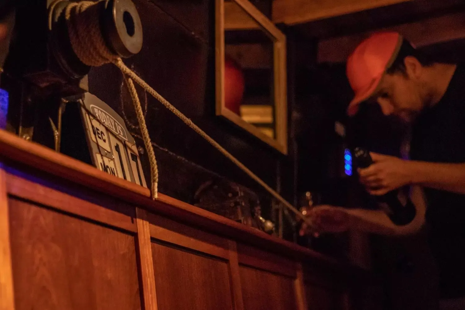 Mann mit roter Kappe und Taschenlampe untersucht eine Holzwand mit altem Kalenderschild