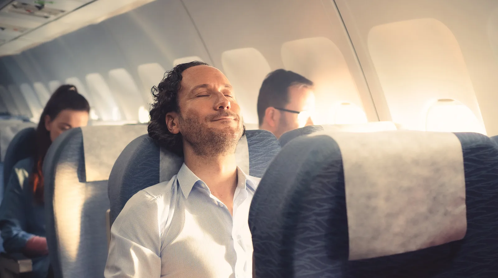 Entspannter Passagier mit geschlossenen Augen im Sitz einer Flugzeugkabine