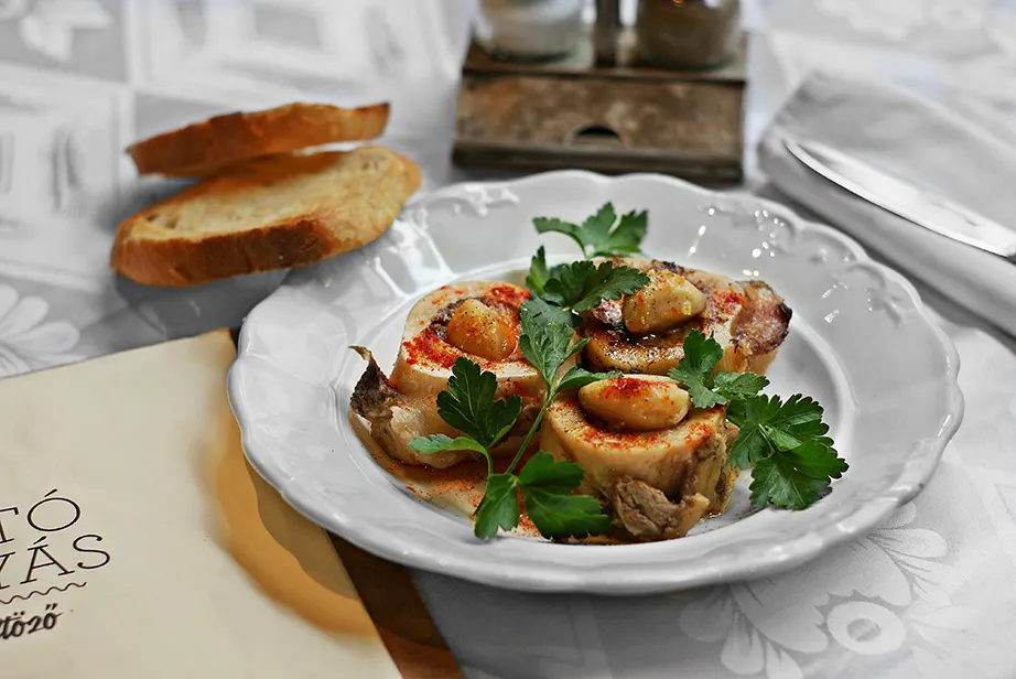 Knochenmark auf geröstetem Weißbrot mit Paprikapulver und Petersilie, daneben Brotscheiben