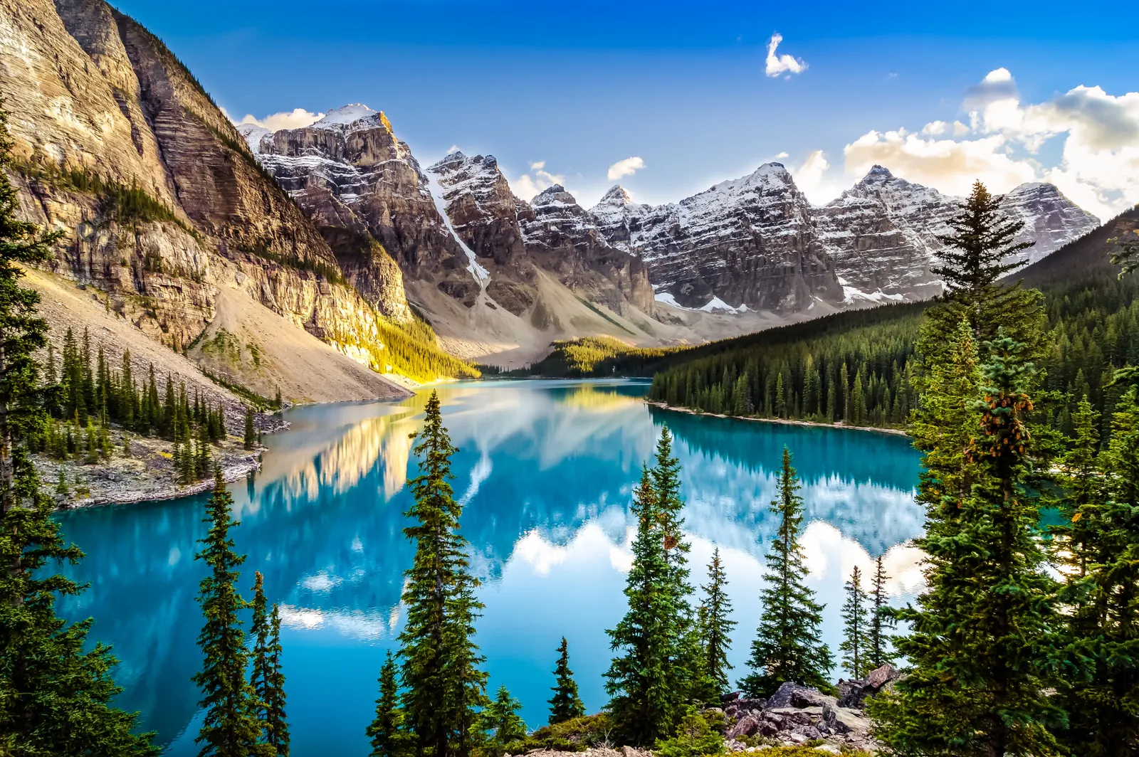 Türkisfarbener Bergsee vor schneebedeckten Gipfeln der Rocky Mountains, umgeben von Nadelwald