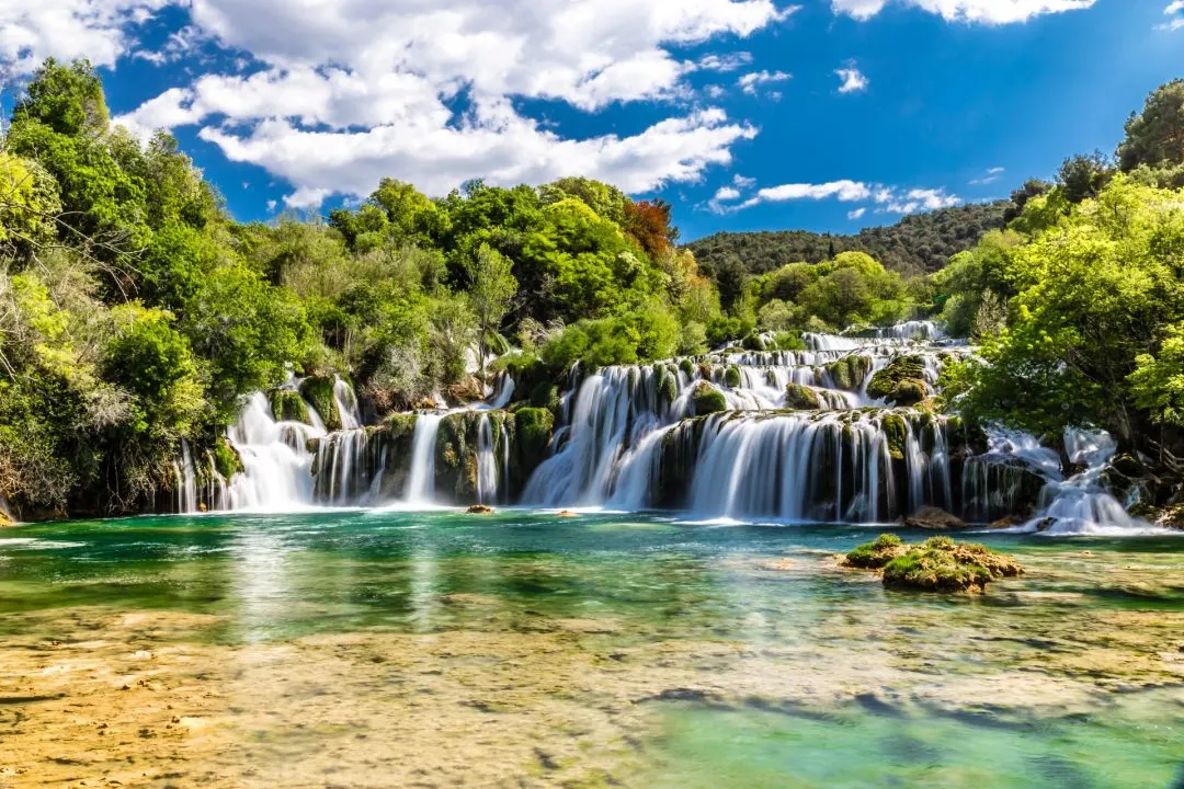 Breite Kaskaden des Krka-Wasserfalls stürzen in einen türkisgrünen Naturpool