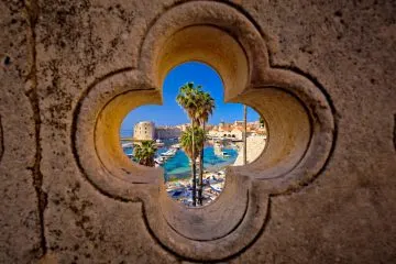 Blick durch ein kleeblattförmiges Steinfenster auf den alten Hafen von Dubrovnik