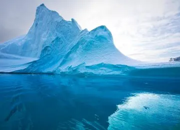 Eisberg über und unter der Wasseroberfläche in klarem türkisfarbenem Meer