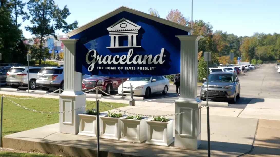 Blaues Schild „Graceland – The Home of Elvis Presley“ am Parkplatz zwischen weißen Pfeilern