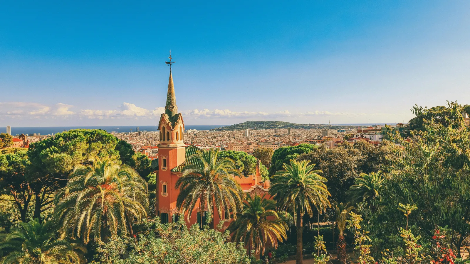 Blick vom Park Güell über Palmen und das Gaudí-Haus auf Barcelona und das Meer