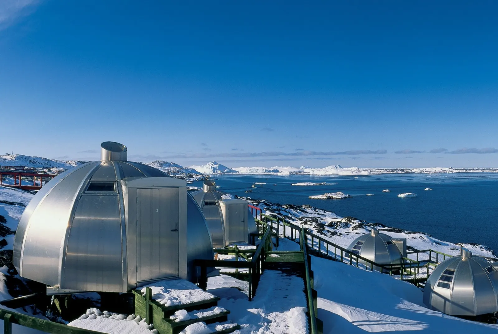 Reihe von Aluminium-Iglus im Schnee unter blauem Himmel an der Eisbucht