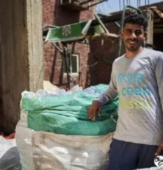 Mitarbeiter eines Sammelprojekts neben prall gefüllten Säcken mit eingesammeltem Plastikmüll