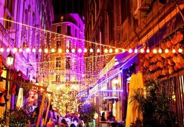Gasse in Istanbul bei Nacht mit Lichterketten, Lampions und besetzten Restauranttischen
