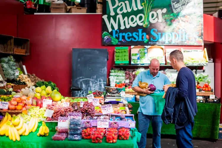 Kunde am Obst- und Gemüsestand Paul Wheeler Fresh Supplies in der Markthalle