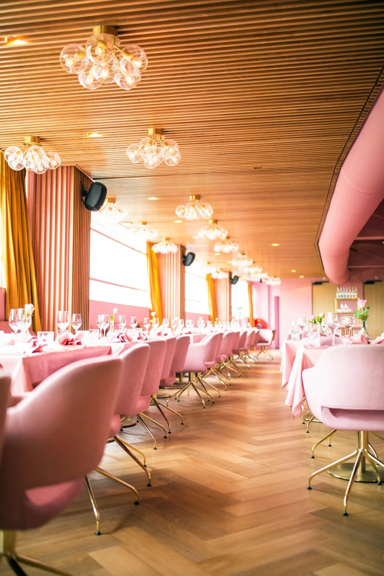 Rosa Speisesaal des MaMa Kelly mit Samtstühlen, Fischgrätparkett und Traubenleuchten