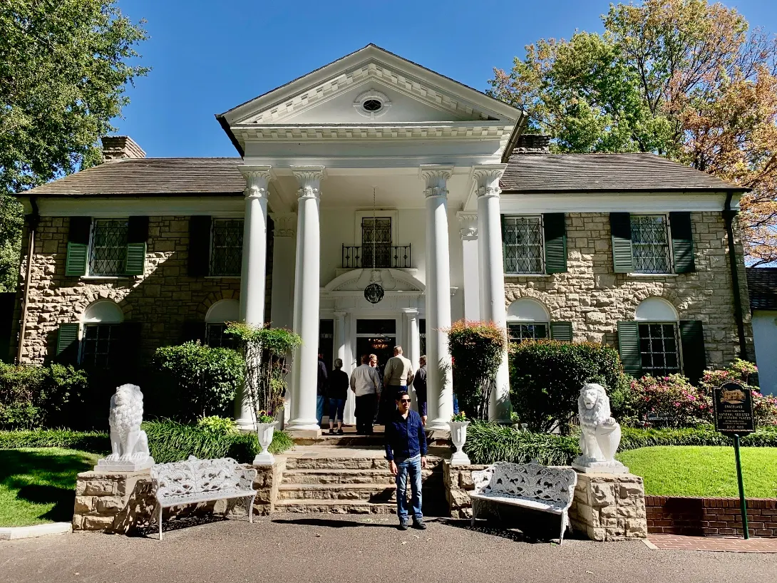Weiße Säulenveranda der Graceland-Villa mit steinernen Löwen, Besucher auf der Treppe