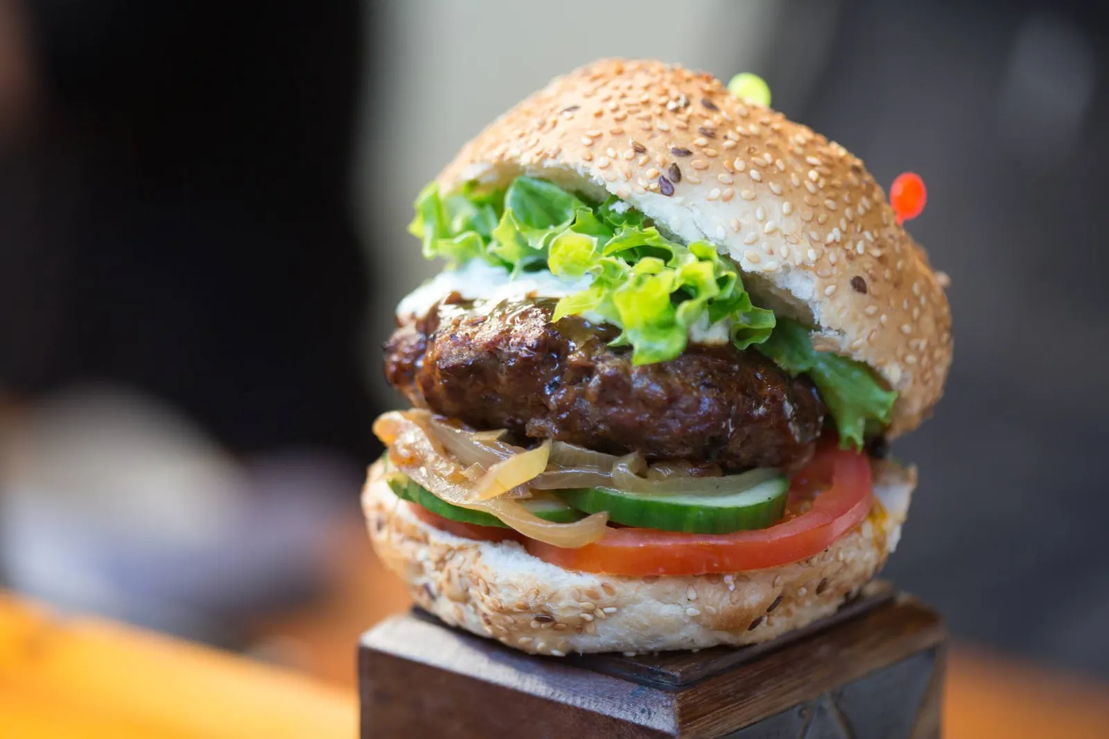 Burger mit Salat, Tomate und Gurke auf einem Holzblock am Marktstand