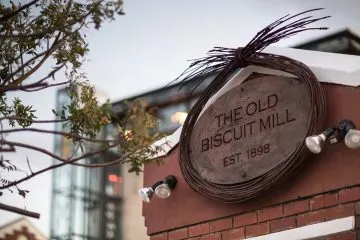 Steinschild The Old Biscuit Mill Est. 1898 an einer Ziegelmauer in Kapstadt