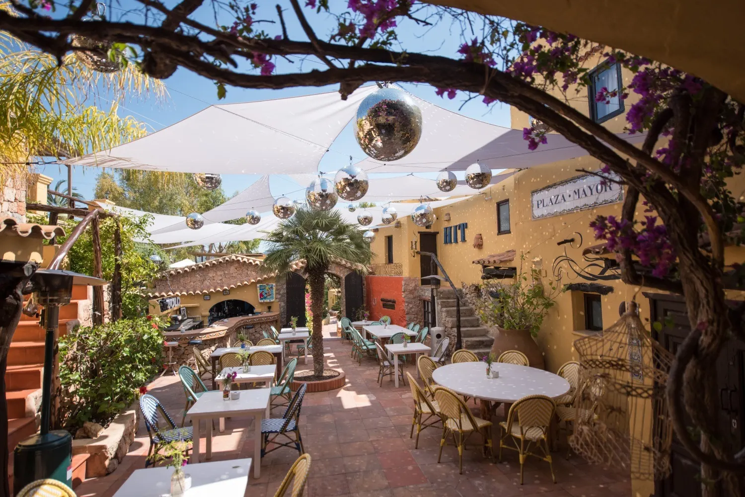 Leerer Innenhof bei Tag mit Bistrotischen, Discokugeln und dem Schild Plaza Mayor