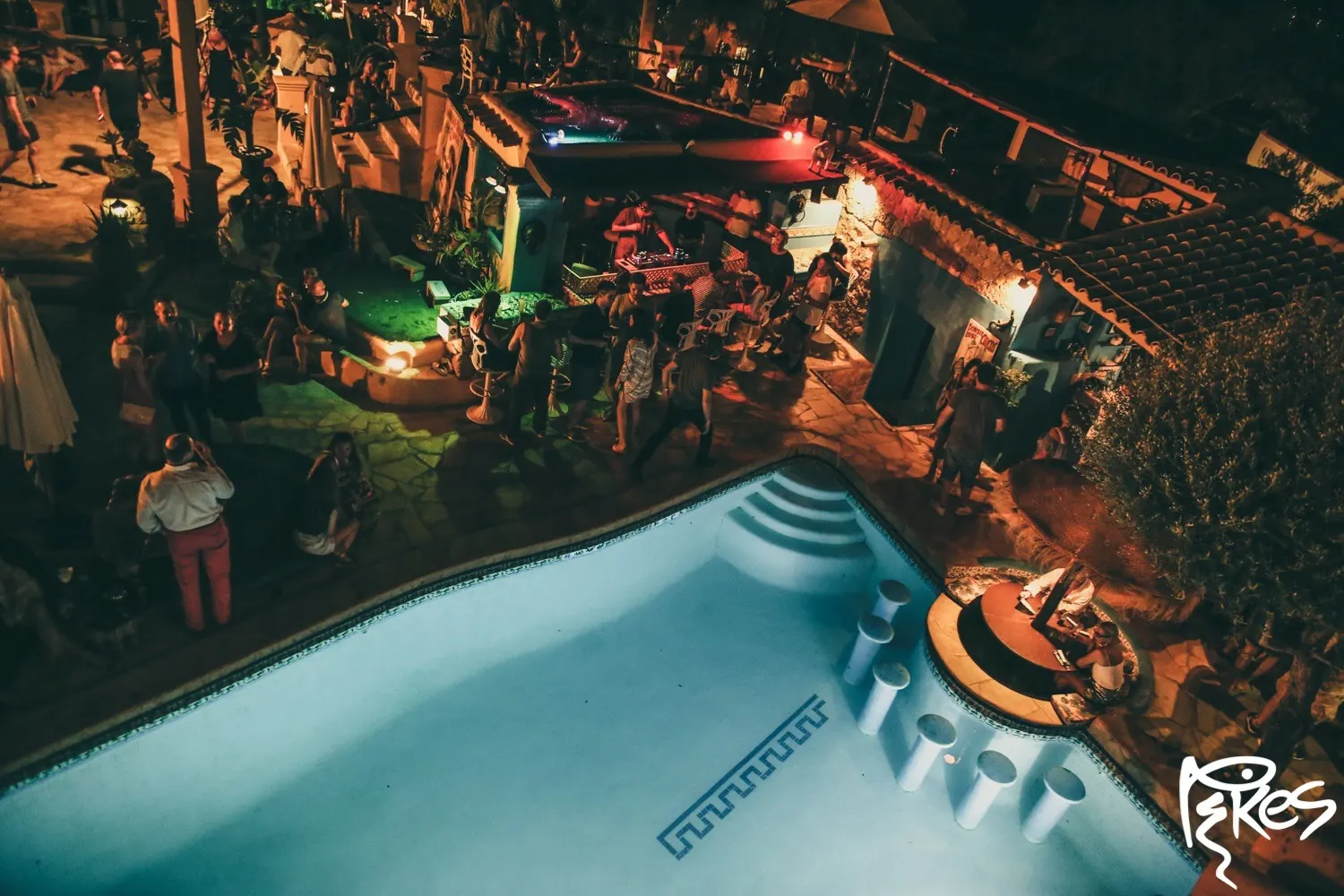 Nachtaufnahme von oben: beleuchteter Pool, feiernde Menschen und rechts der Pikes-Schriftzug
