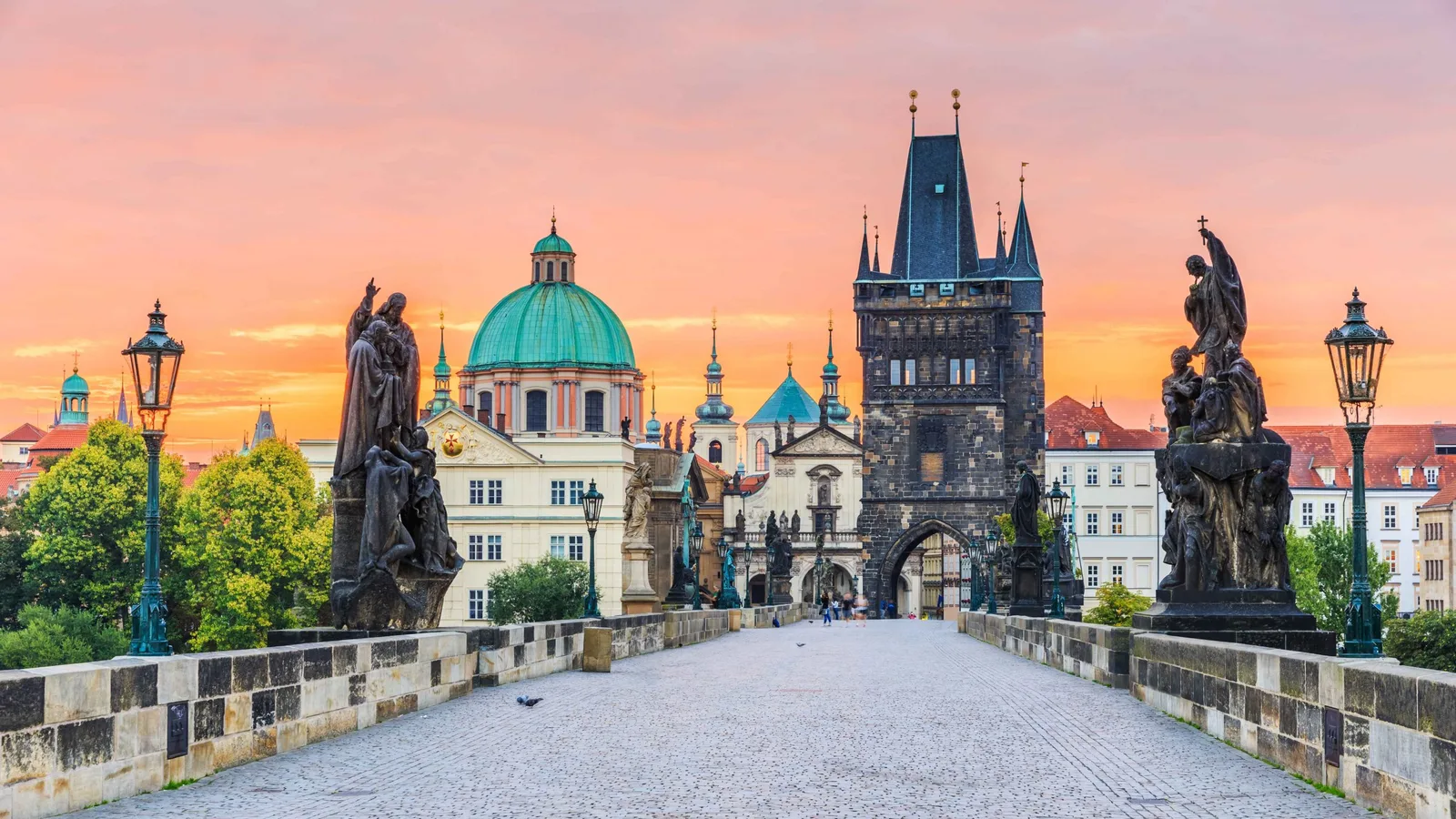 Blick über die menschenleere Karlsbrücke mit Statuen und Brückenturm im Morgenrot