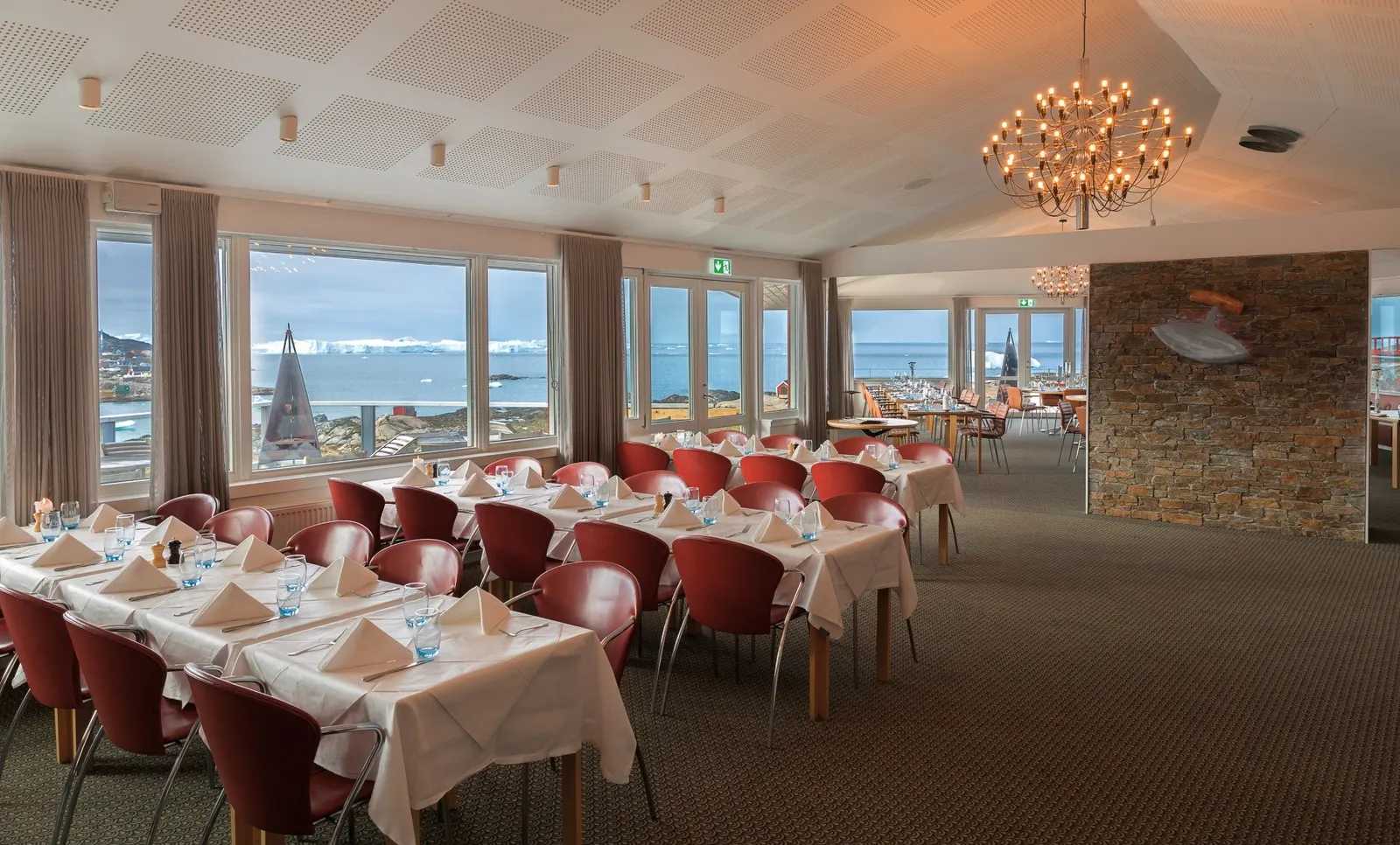 Großer Speisesaal des Restaurant Ulo mit roten Stühlen, Kronleuchter und Fjordblick