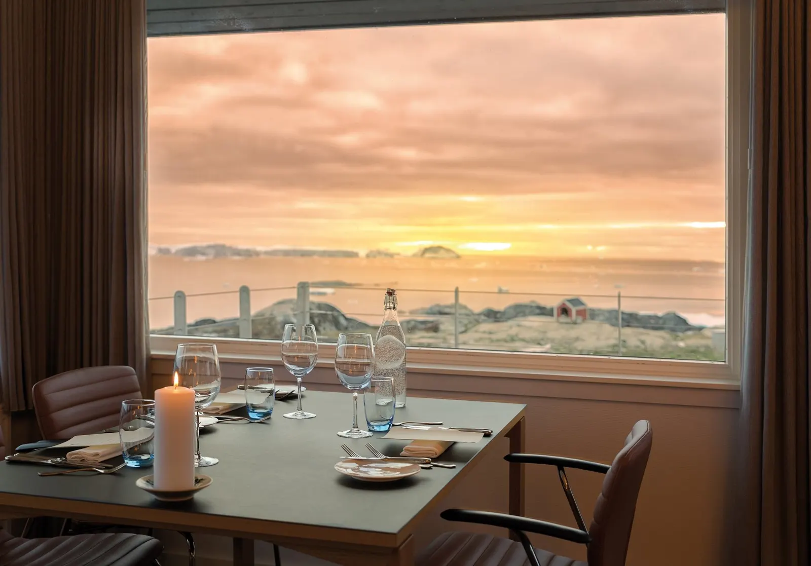 Gedeckter Tisch am Fenster des Restaurant Ulo, Sonnenuntergang über Eisbergen