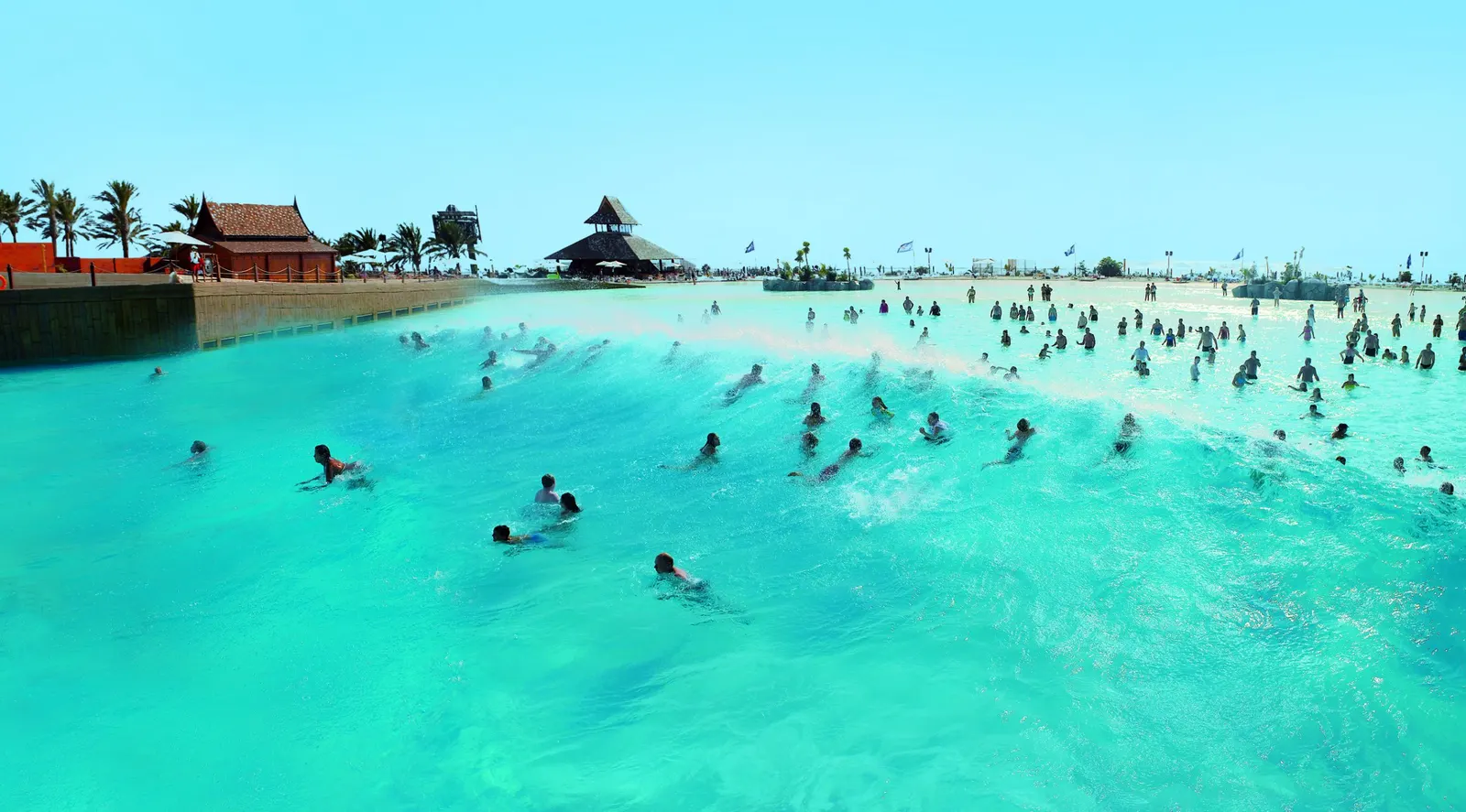 Türkises Wellenbecken des Siam Park mit Schwimmern, Pavillons und Sandstrandkante