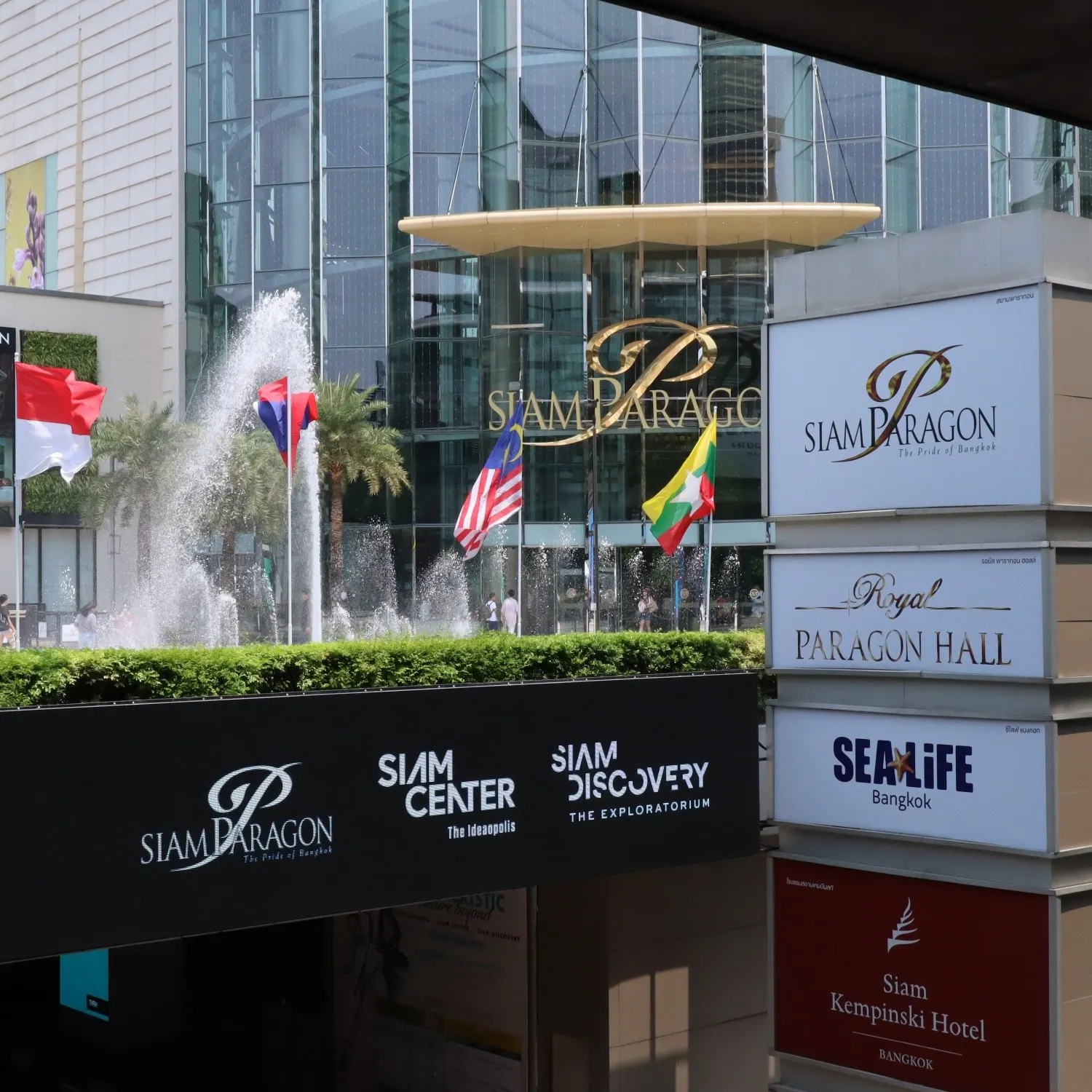 Springbrunnen und Flaggen vor dem Siam Paragon, daneben Wegweiser zu Siam Center und Sealife