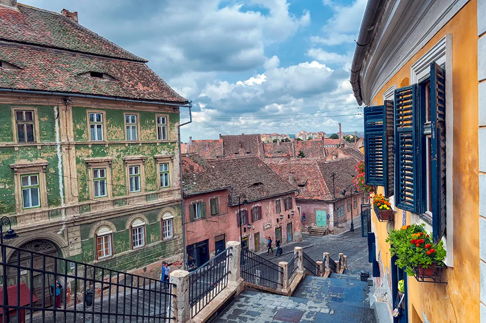 Blick von einer Treppe auf Altstadthäuser mit grüner Fassade und roten Ziegeldächern