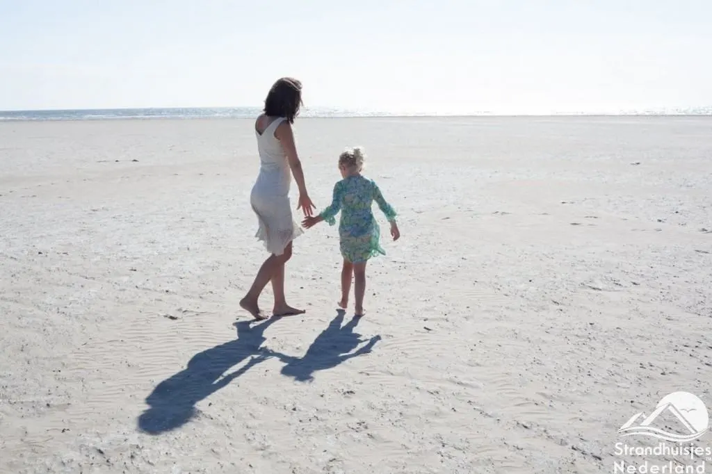Frau und Mädchen gehen über den weiten hellen Sandstrand von Bloemendaal zum Meer