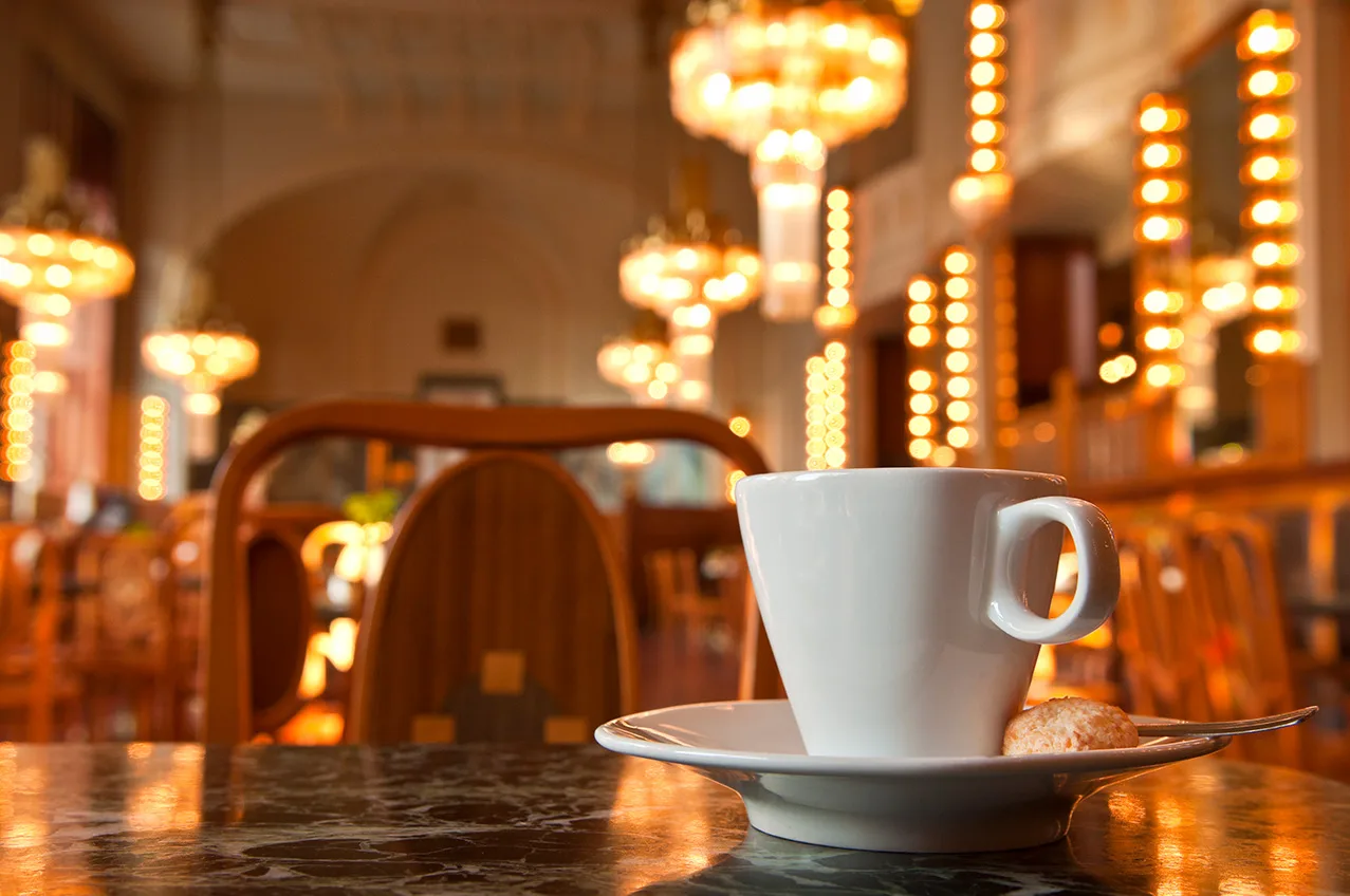 Weiße Kaffeetasse auf einem Marmortisch in einem festlich beleuchteten Kaffeehaus