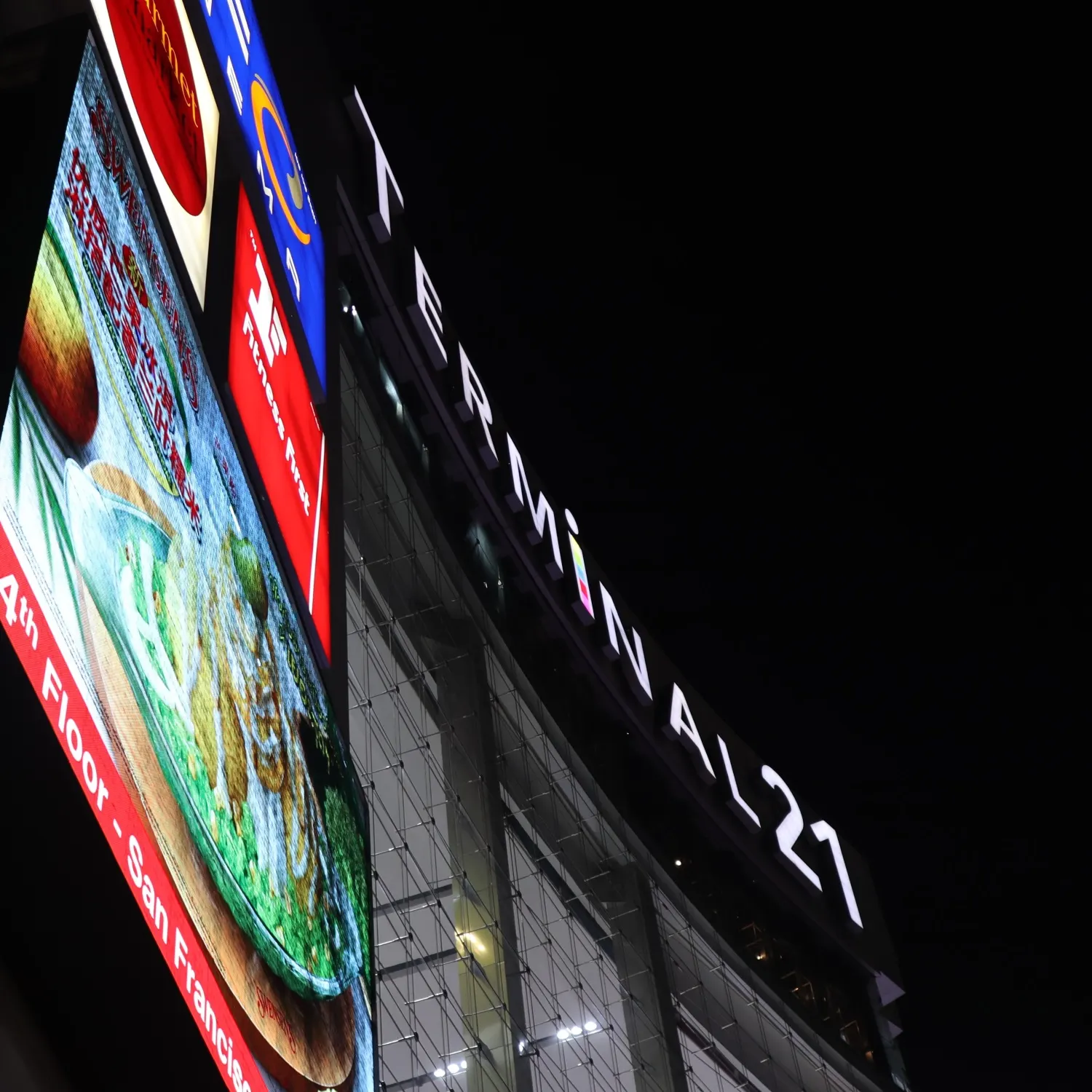 Beleuchteter Schriftzug Terminal 21 an der Fassade des Einkaufszentrums bei Nacht