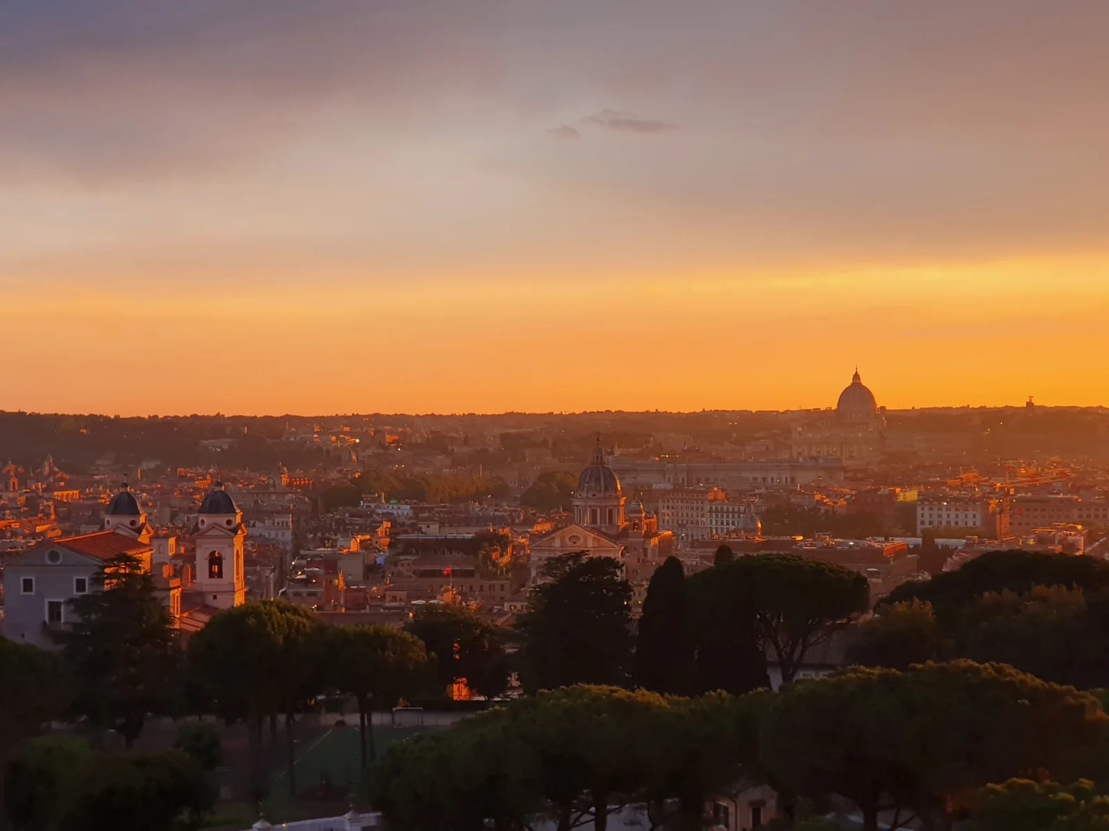 Sonnenuntergang über den Dächern Roms mit der Kuppel des Petersdoms am Horizont