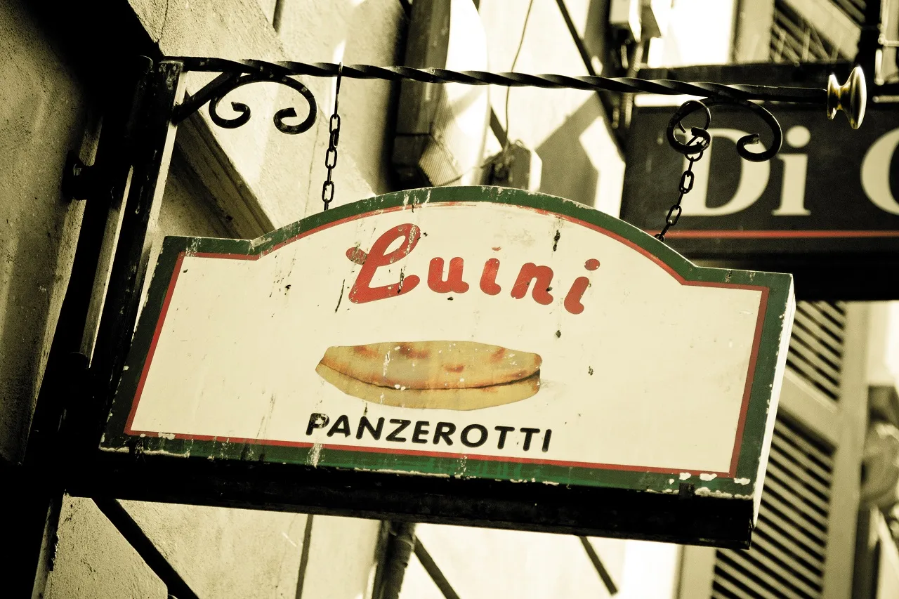 Altes bemaltes Ladenschild von Luini mit Panzerotto-Motiv an einer Hauswand